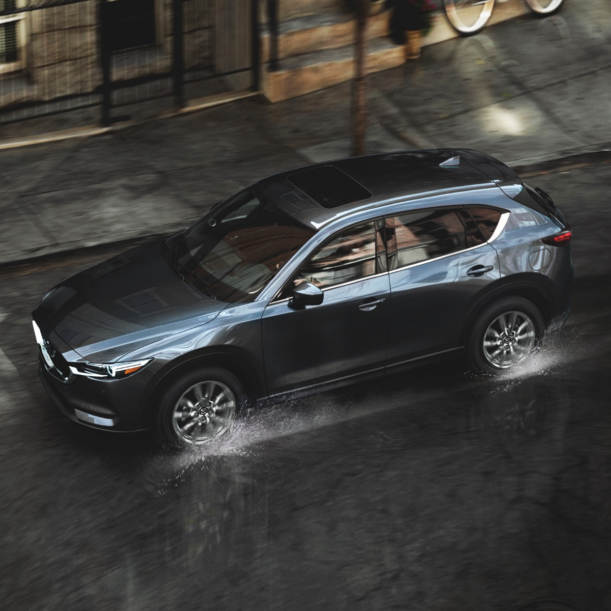 Aerial view of a 2021 Mazda CX-5 driving down a city road in the rain
