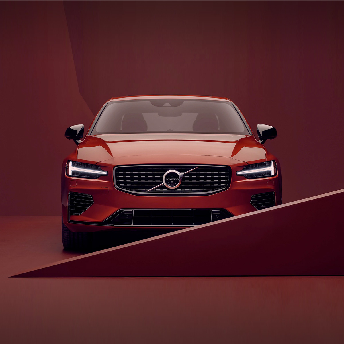 Front, head-on shot of a 2021 Volvo S60 with a red, abstract background