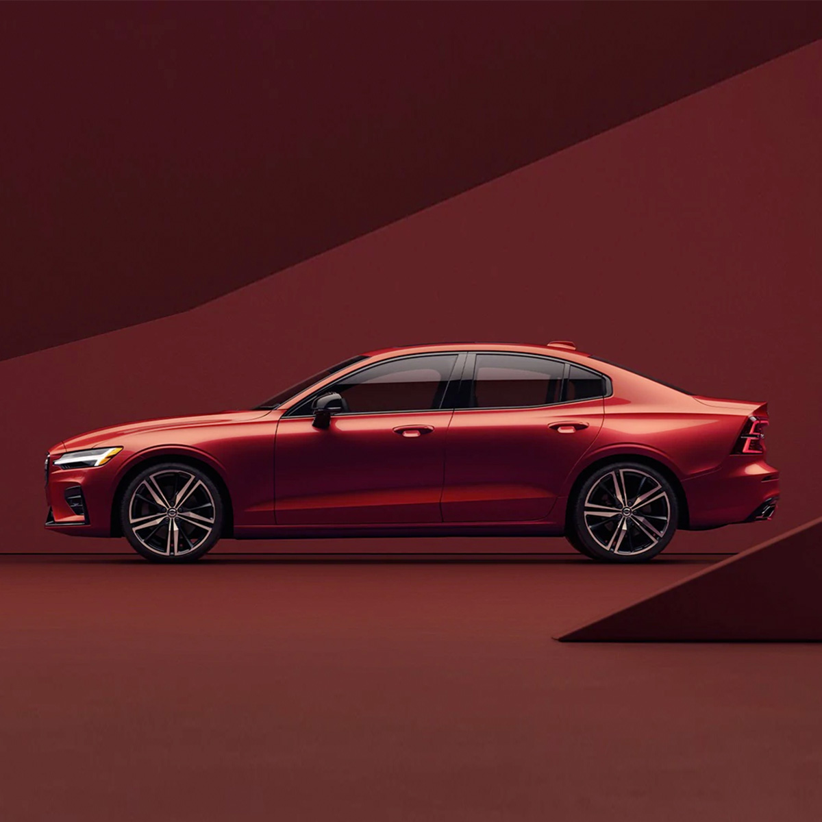Side shot of a 2021 Volvo S60 with a red, abstract background
